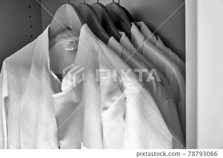White smocks on wooden hangers hang in the cupboard of a laboratory, Black and white, bw White smocks on wooden hangers hang in the cupboard of a laboratory, Black and white, bw 78793066