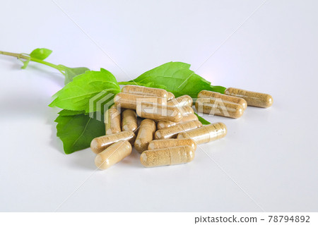Herbal capsules over green herb leaf on white. Herbal capsules over green herb leaf on white. 78794892