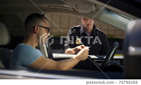 Female police officer checking documents of male driver Female police officer checking documents of male driver 78798268