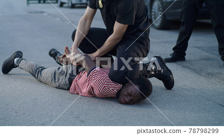 Policeman putting handcuffs on crying black man 78798299