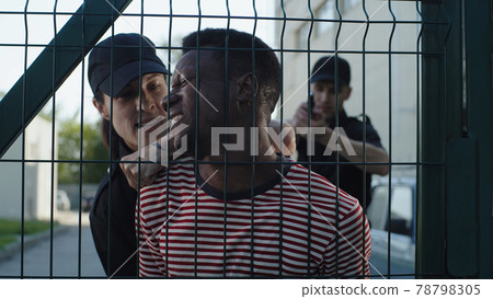 Police office interrogating African American man near grate 78798305