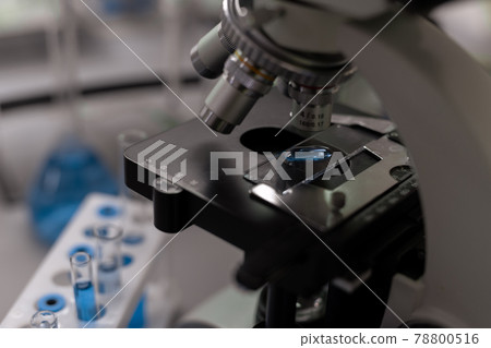 Part of microscope and flasks with blue liquid substance Part of microscope and flasks with blue liquid substance 78800516