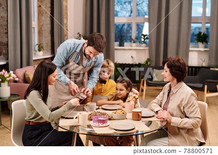 Young man pouring black tea into cup of his wife Young man pouring black tea into cup of his wife 78800571