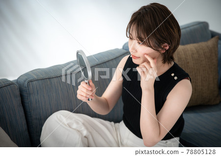 Young woman looking at a mirror 78805128