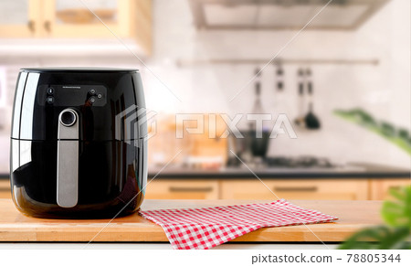 An electric Air Fryer on table with blurred kitchen background.  Lifestyle of new normal cooking. 78805344