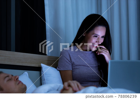 Woman sitting on bed in the night and using laptop computer 78806239