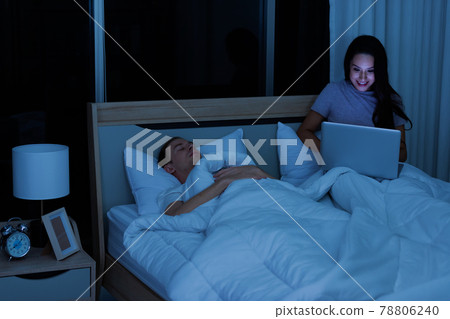 Woman sitting on bed in the night and using laptop computer 78806240