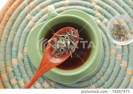 top view of green tea and herbal leaf in a small glass bowl on table  78807475