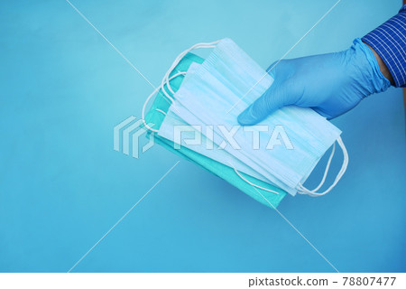 hand in medical glovers holding surgical face mask,  78807477