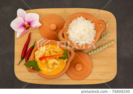 Chicken Panang Curry with Rice is Thai food sauce curry and basil leaf and coconut milk put on Terracotta pot on a banana leaf in wooden background 78808200