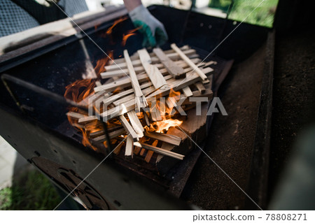 A man in gloves kindles fire from stacked wood. Preparation for a barbecue. A man in gloves kindles fire from stacked wood. Preparation for a barbecue. 78808271
