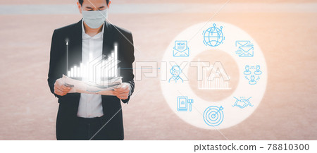 The image face of a Business Asian man wearing a doctor mask to prevent germs, toxic fumes, and COVID 19, He is reading and listening to the news on tablets and newspapers, do not work in the park. 78810300