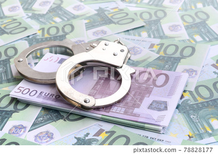 Police handcuffs lies on a set of green monetary denominations of 100 euros. A lot of money forms an infinite heap Police handcuffs lies on a set of green monetary denominations of 100 euros. A lot of money forms an infinite heap 78828177