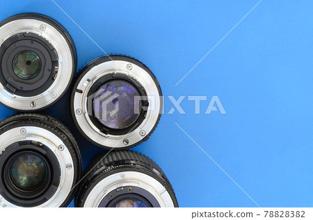 Several photographic lenses lie on a bright blue background. Space for text 78828382