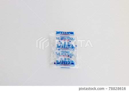 Desiccant silica on the pack. Closeup view. packet of silica gel buried in silica crystals. There are words "desiccant on packet. Desiccant silica on the pack. Closeup view. packet of silica gel buried in silica crystals. There are words "desiccant on packet. 78828616