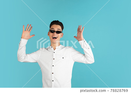 Young Caucasian boy in white shirt isolated on blue studio background. Concept of facial expressions, human emotions. 78828769