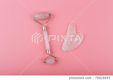 Top view of jade roller and heart shaped massager made of pink quartz on pink background. Guasha massage concept 78828843