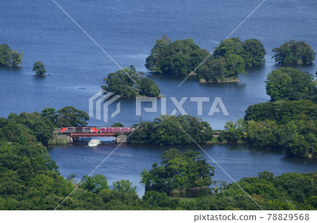 A freight train that intersects with a pleasure boat that goes around Onuma and Onuma near Tsukimi Bridge 78829568