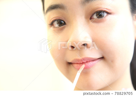 Young woman applying lip gloss Young woman applying lip gloss 78829705