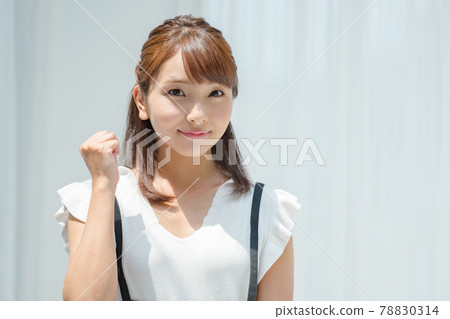 一個穿著夏裝的年輕女子在白牆前接受陽光 78830314
