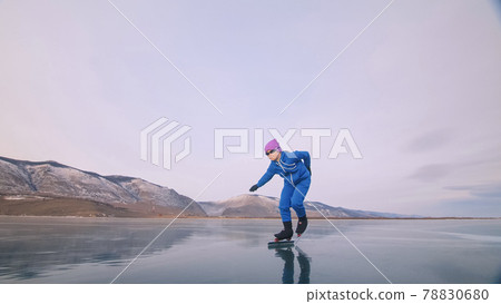 The child train on ice professional speed skating. The girl skates in the winter in sportswear, sport glasses, suit. Outdoor slow motion. 78830680
