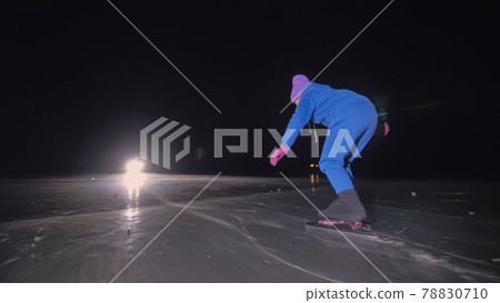 The child train on ice speed skating. The night skating. The girl skates in the winter in sportswear, sport glasses. Outdoor slow motion. 78830710