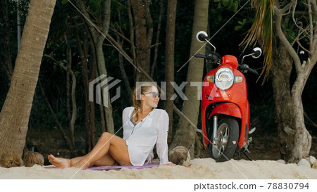 Scooter road trip. Woman alone on red motorbike in white clothes on sand beach by ocean. One girl caucasian tourist walk near tropical palm tree. 78830794