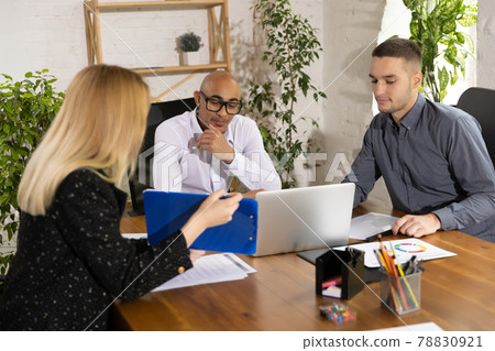 Young men and woman, office workers, colleagues working togerther in business office,. Concept of teamwork, coworking Young men and woman, office workers, colleagues working togerther in business office,. Concept of teamwork, coworking 78830921