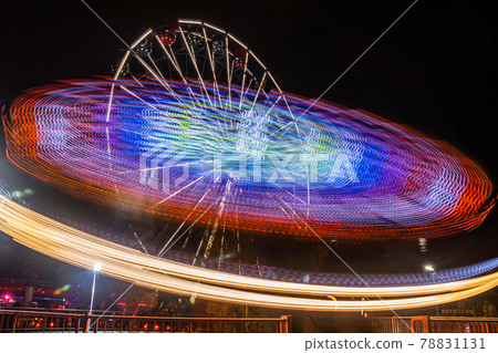 Two rides in motion in amusement park, night illumination. Long exposure. Two rides in motion in amusement park, night illumination. Long exposure. 78831131