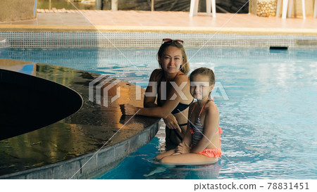 The pretty woman drinking blue cocktail alcohol liquor and sit at the bar. Cocktail bar in the swimming pool. Portrait of sexy girl in pool outdoor. The pretty woman drinking blue cocktail alcohol liquor and sit at the bar. Cocktail bar in the swimming pool. Portrait of sexy girl in pool outdoor. 78831451