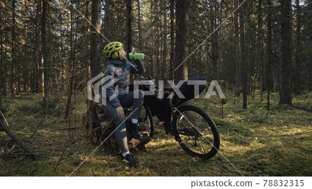 The woman travel on mixed terrain cycle touring with bike bikepacking. The traveler journey with bicycle bags. Magic forest park. The woman travel on mixed terrain cycle touring with bike bikepacking. The traveler journey with bicycle bags. Magic forest park. 78832315