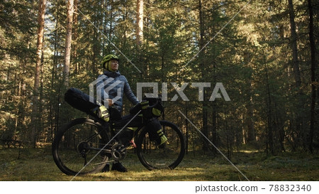 The woman travel on mixed terrain cycle touring with bike bikepacking. The traveler journey with bicycle bags. Magic forest park. 78832340