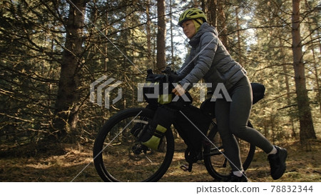 The woman travel on mixed terrain cycle touring with bike bikepacking. The traveler journey with bicycle bags. Magic forest park. The woman travel on mixed terrain cycle touring with bike bikepacking. The traveler journey with bicycle bags. Magic forest park. 78832344