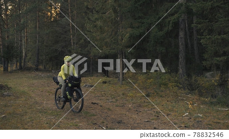 The woman travel on mixed terrain cycle touring with bike bikepacking. The traveler journey with bicycle bags. Magic forest park. 78832546