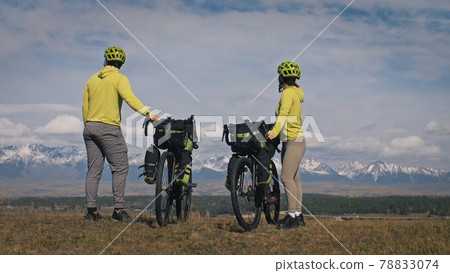 The man and woman travel on mixed terrain cycle touring with bikepacking. The love couple journey with tent in with bicycle bags. Stylish sportswear. The man and woman travel on mixed terrain cycle touring with bikepacking. The love couple journey with tent in with bicycle bags. Stylish sportswear. 78833074