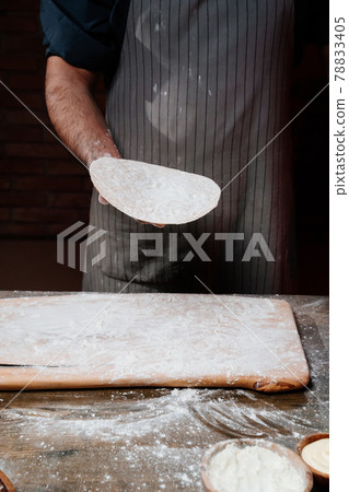 men's hands hold a thin flatbread. Cooking pizza, noodles or pitta at home men's hands hold a thin flatbread. Cooking pizza, noodles or pitta at home 78833405