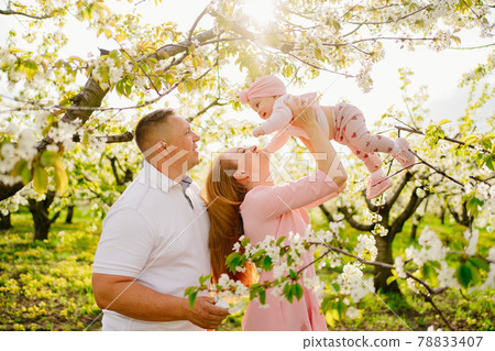 family with a baby daughter in spring flowering garden. cleft lip in infants. family with a baby daughter in spring flowering garden. cleft lip in infants. 78833407