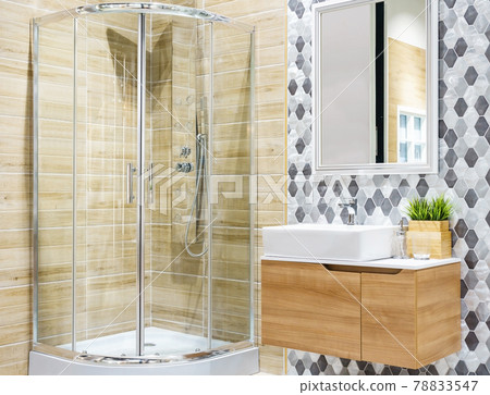 Spacious and bright modern bathroom interior with white walls, a shower cabin with glass wall, a toilet and faucet sink 78833547