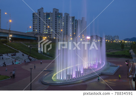 在公園的噴泉表演後面可以看到這座城市的公寓。 78834591