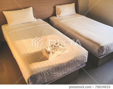 Clean white towel on white clean bedroom in the budget hotel for traveller with sunset light from the window Clean white towel on white clean bedroom in the budget hotel for traveller with sunset light from the window 78834610