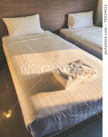 Clean white towel on white clean bedroom in the budget hotel for traveller with sunset light from the window Clean white towel on white clean bedroom in the budget hotel for traveller with sunset light from the window 78834612