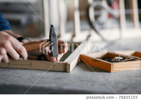 Carpenter hammering a nail in a workshop Carpenter hammering a nail in a workshop 78835155