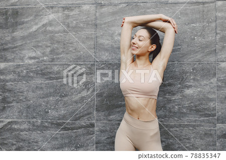 Woman practicing advanced yoga against a dark urban wall Woman practicing advanced yoga against a dark urban wall 78835347