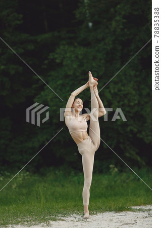 Woman practicing advanced yoga in a beach 78835388