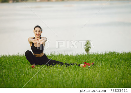 Woman practicing advanced yoga by the water 78835411