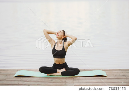 Woman practicing advanced yoga by the water 78835453