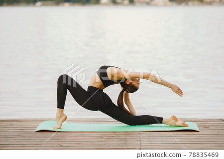 Woman practicing advanced yoga by the water 78835469
