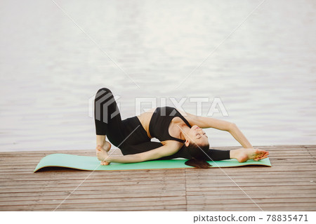 Woman practicing advanced yoga by the water Woman practicing advanced yoga by the water 78835471