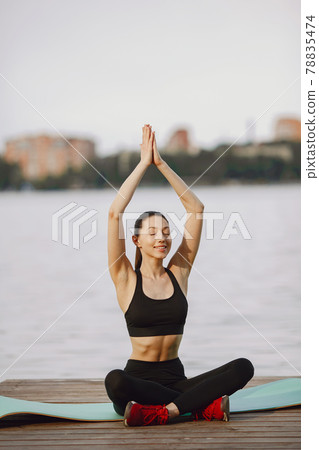 Woman practicing advanced yoga by the water Woman practicing advanced yoga by the water 78835474