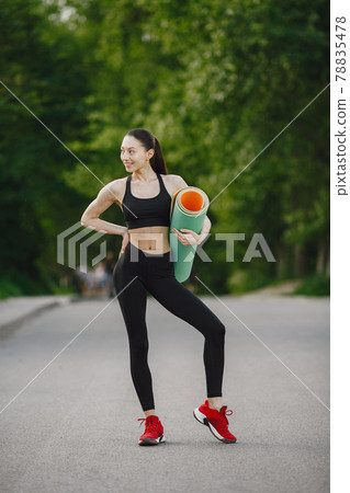 Woman in a black spoerswear standing in a forest Woman in a black spoerswear standing in a forest 78835478